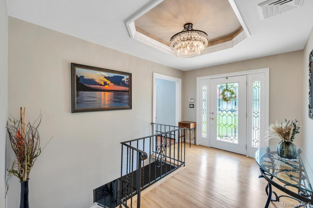 10 South Lot Road Smithtown, NY 11787 - Photo 6 of 50 Entryway featuring wood-finish flooring, a decorative glass paneled front door, and a coffered ceiling with a chandelier
