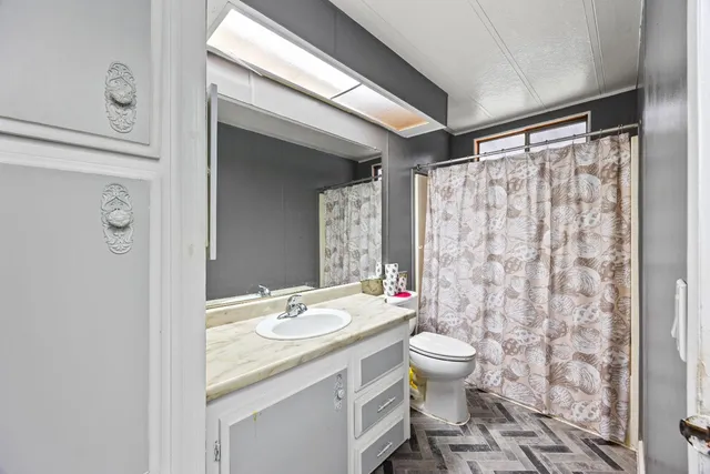 a bathroom with a granite countertop sink toilet mirror and shower