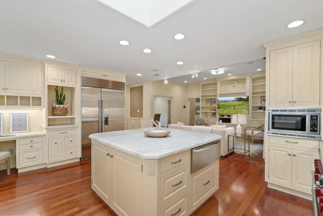 a kitchen with sink stove and white cabinets with wooden floor