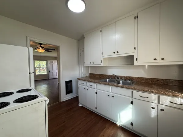 a kitchen with granite countertop a sink a stove and cabinets