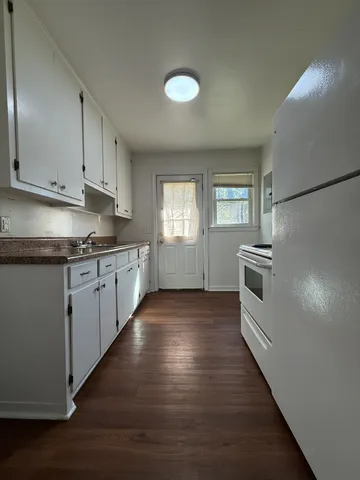 a kitchen with granite countertop white cabinets and white appliances