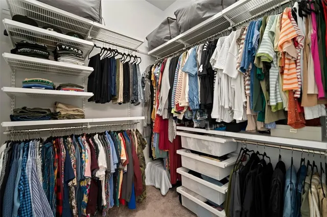 a view of walk in closet with clothes and shoes
