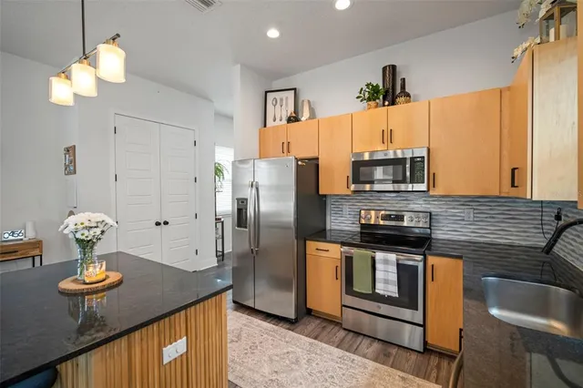 a kitchen with stainless steel appliances granite countertop a sink a stove and a refrigerator