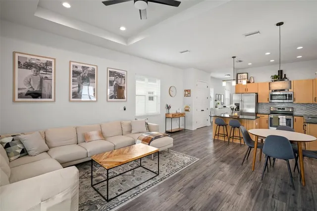 a living room with furniture kitchen view and a wooden floor