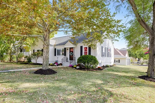 a front view of a house with a garden and trees