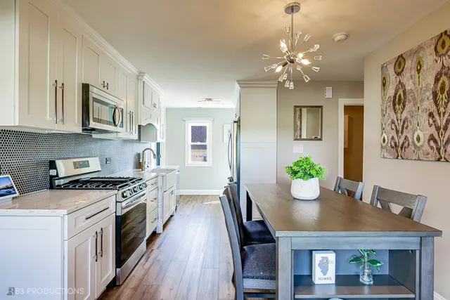 a open kitchen with stainless steel appliances granite countertop a stove top oven a dining table and chairs with wooden floor