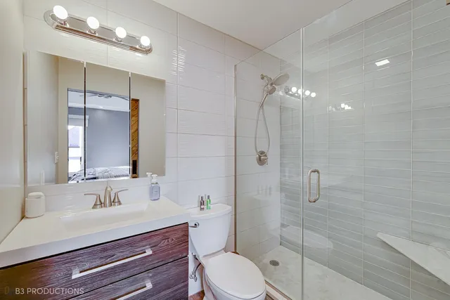 a bathroom with a sink a toilet a mirror and shower