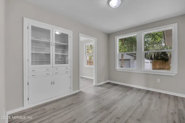 an empty room with wooden floor and windows