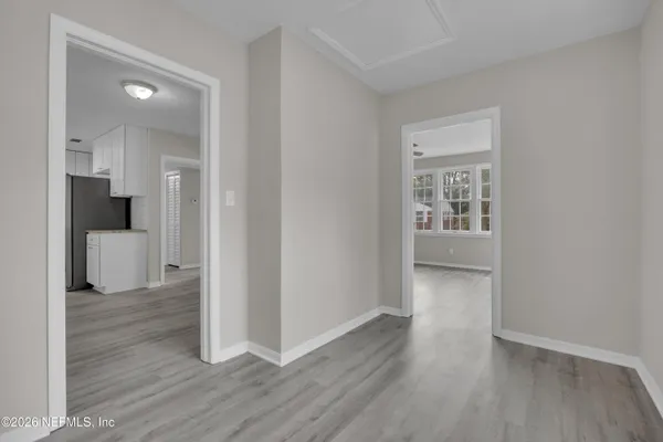 a view of a hallway with wooden floor and a bathroom