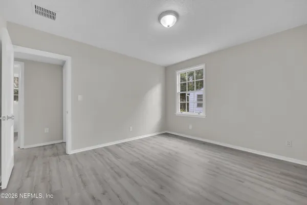 an empty room with wooden floor and windows