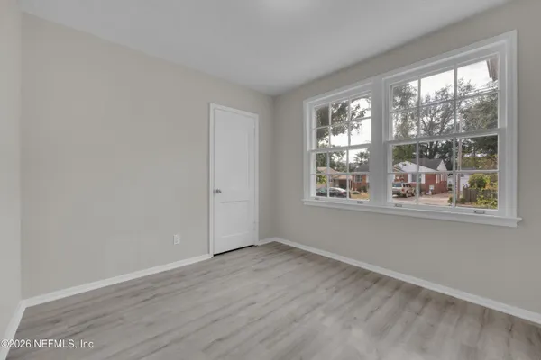 a view of an empty room with wooden floor and a window