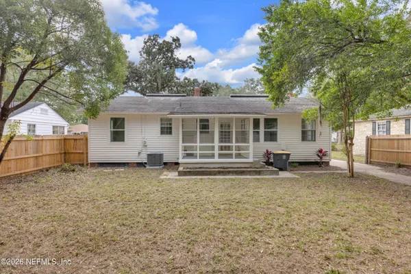 a view of a house with a yard and large tree