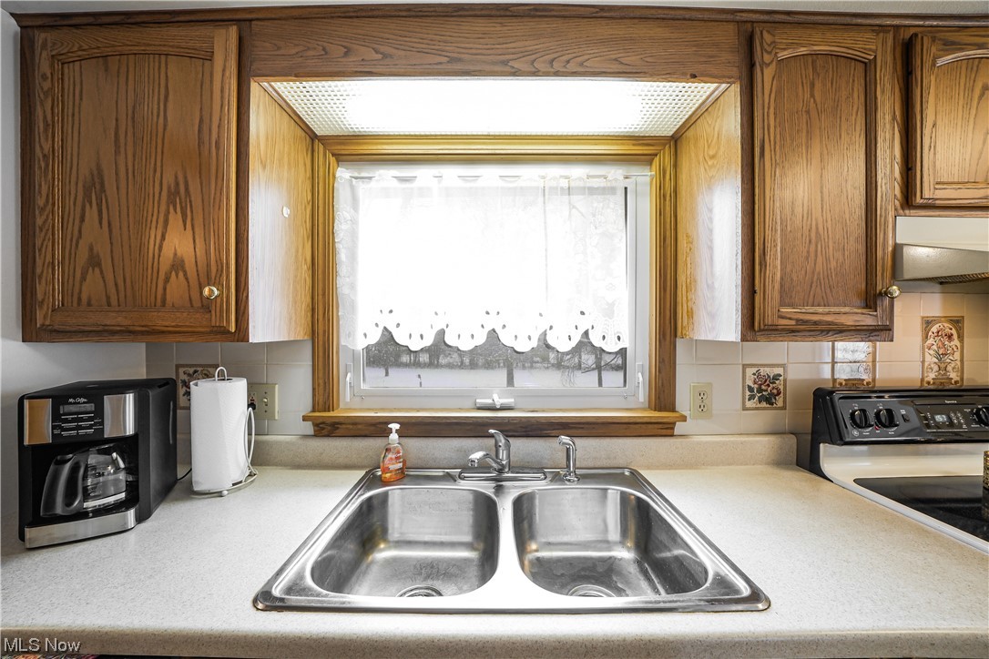 7541 Cooley Road Ravenna, OH 44266 - Photo 12 of 32 Kitchen featuring range, sink, custom range hood, and tasteful backsplash