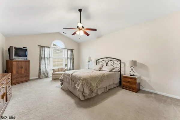 a bedroom with a bed a chandelier and a flat tv screen on a dresser