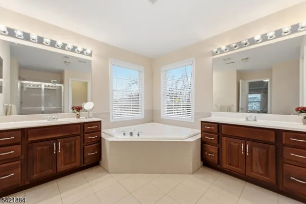 a spacious bathroom with a tub a double vanity sink and a large mirror of cabinet