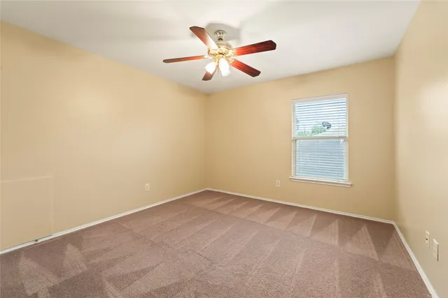 an empty room with window and ceiling fan