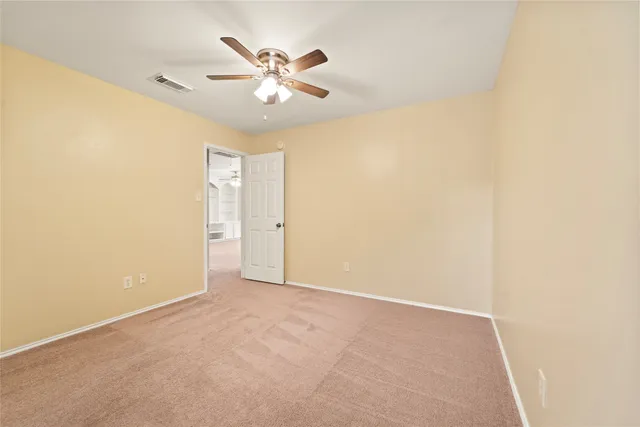 an empty room with a chandelier fan and a window