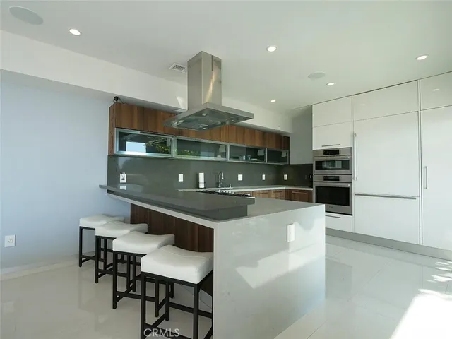 a kitchen with stainless steel appliances a sink a stove and chairs