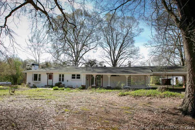a view of a house with a yard and large tree