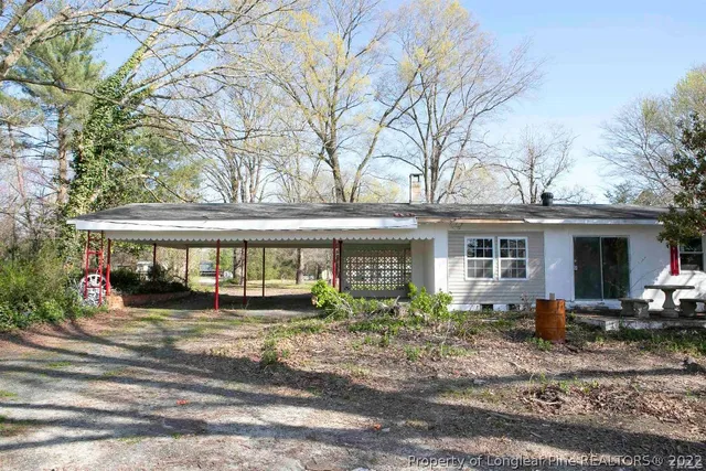a view of a white house with large tree and wooden fence