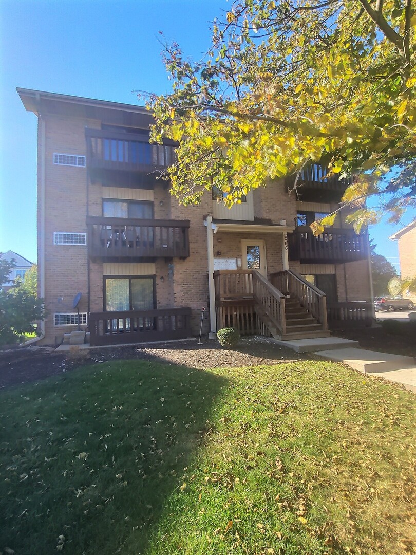 266 12th Street, Unit 3F Wheeling, IL 60090 - Photo 3 of 11 a view of a house with a yard and garage