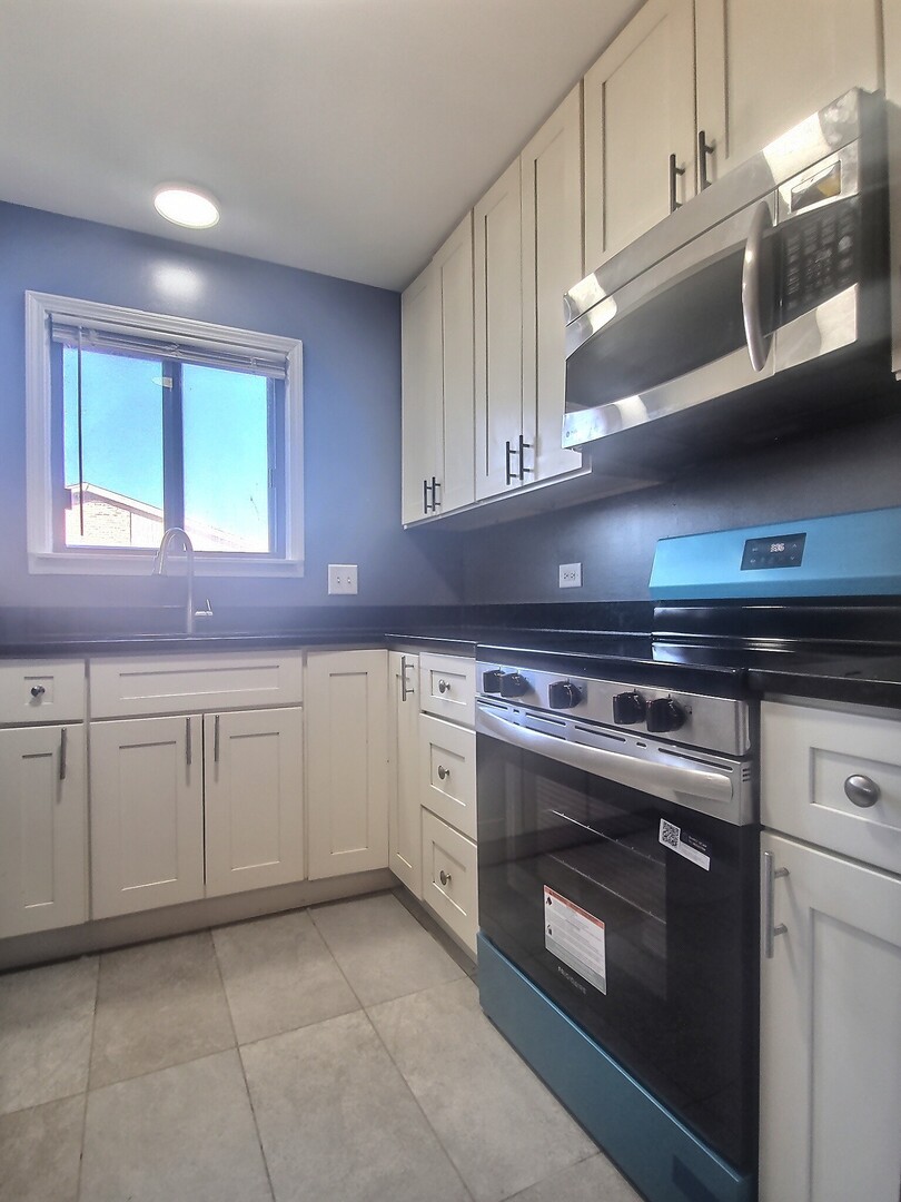266 12th Street, Unit 3F Wheeling, IL 60090 - Photo 6 of 11 a kitchen with stainless steel appliances granite countertop a stove a sink and a microwave