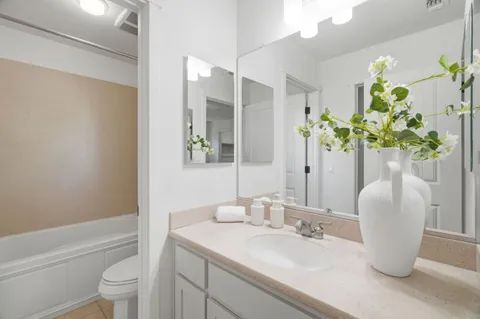 a bathroom with a granite countertop sink a toilet and a mirror