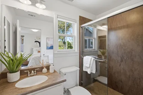 a bathroom with a granite countertop sink toilet a mirror and shower