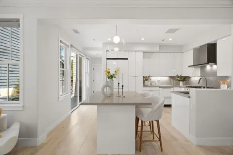 a kitchen with kitchen island granite countertop a sink cabinets and wooden floor