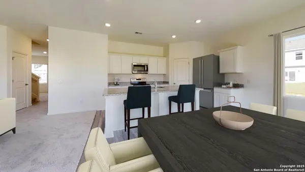 a kitchen with kitchen island granite countertop a sink and a refrigerator