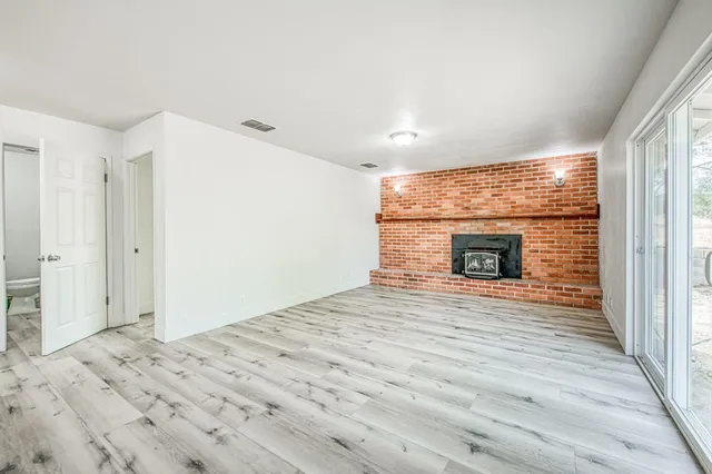 a view of empty room with wooden floor and fireplace