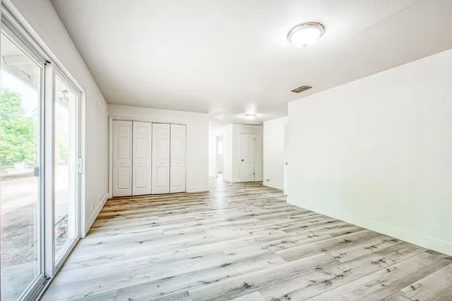 a view of an empty room with wooden floor and a window