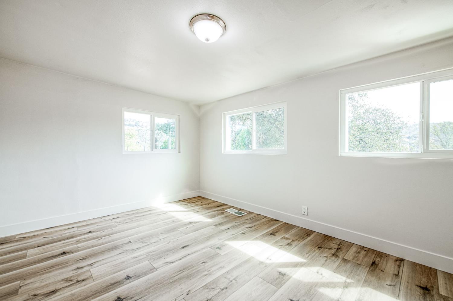 29531 Morgan Canyon Road Prather, CA 93651 - Photo 16 of 42 a view of an empty room with wooden floor and a window