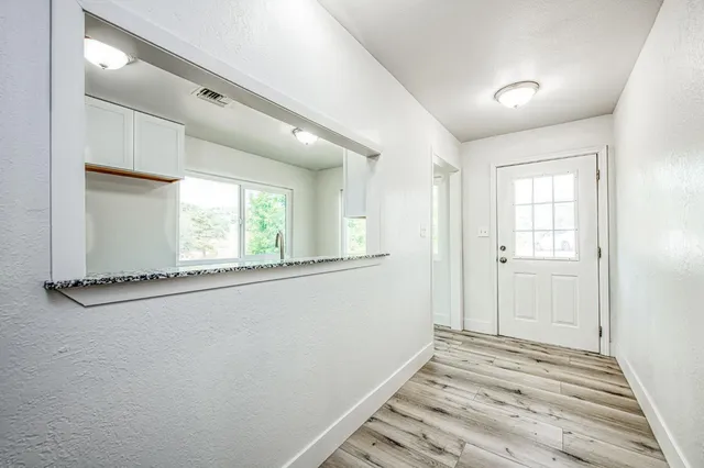a view of empty room with window and wooden floor