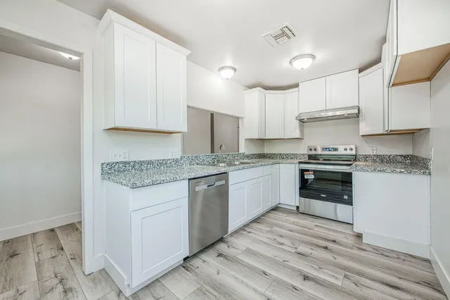 a kitchen with granite countertop white cabinets and white appliances