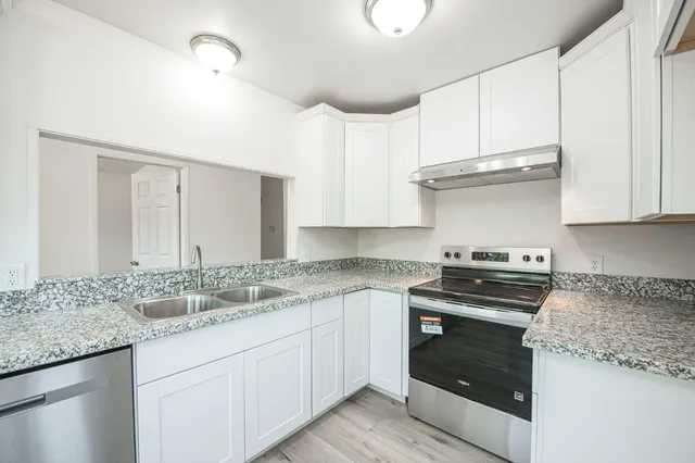 a kitchen with granite countertop a stove sink and cabinets