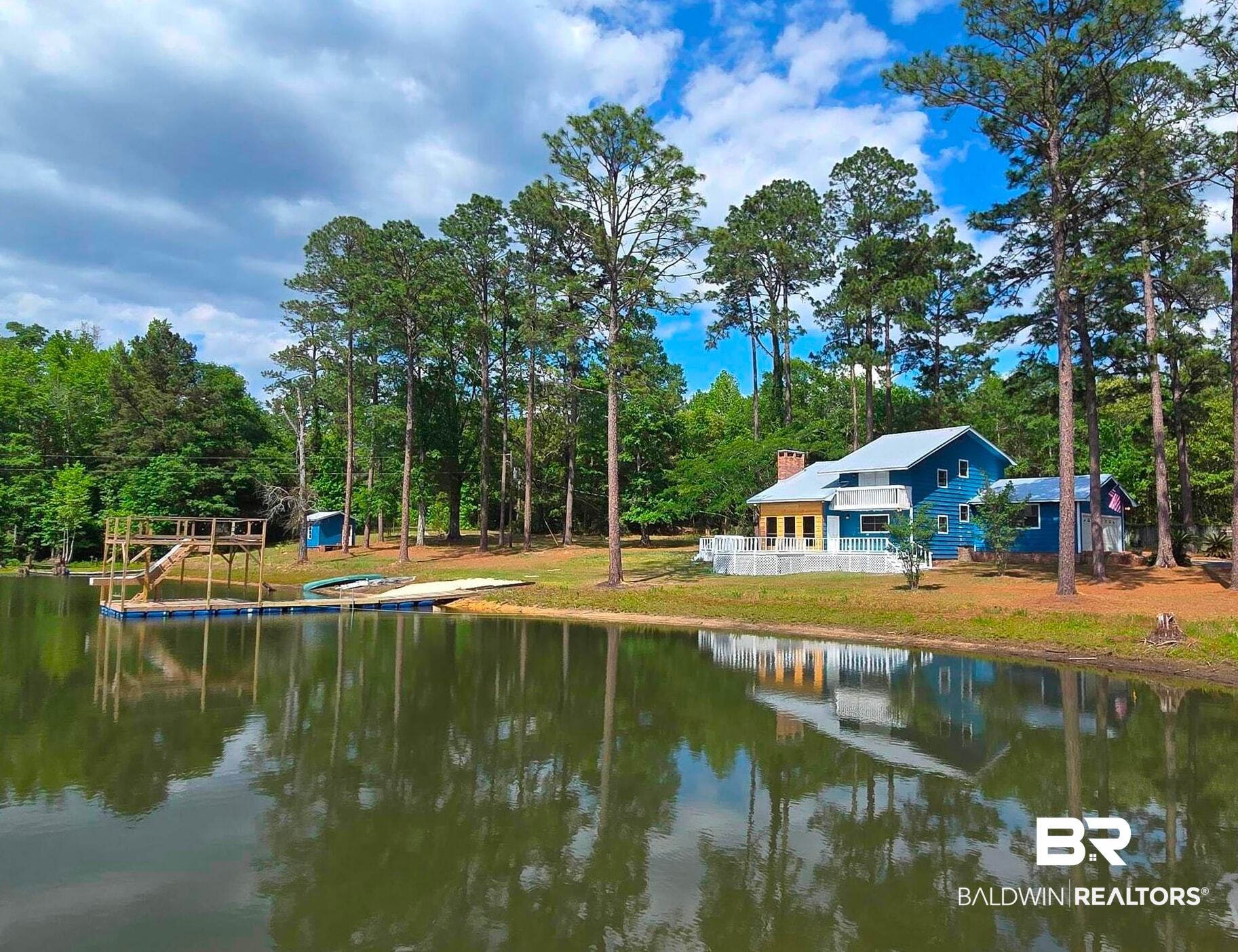 3160 Old Castleberry Road Brewton, AL 36426 - Photo 2 of 36 Waterfront property featuring a blue-sided residence with white trim, a white picket fence, and a private dock structure