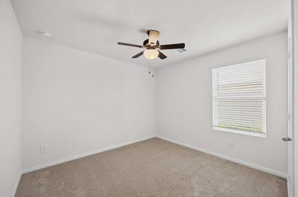 an empty room with a window and a ceiling fan