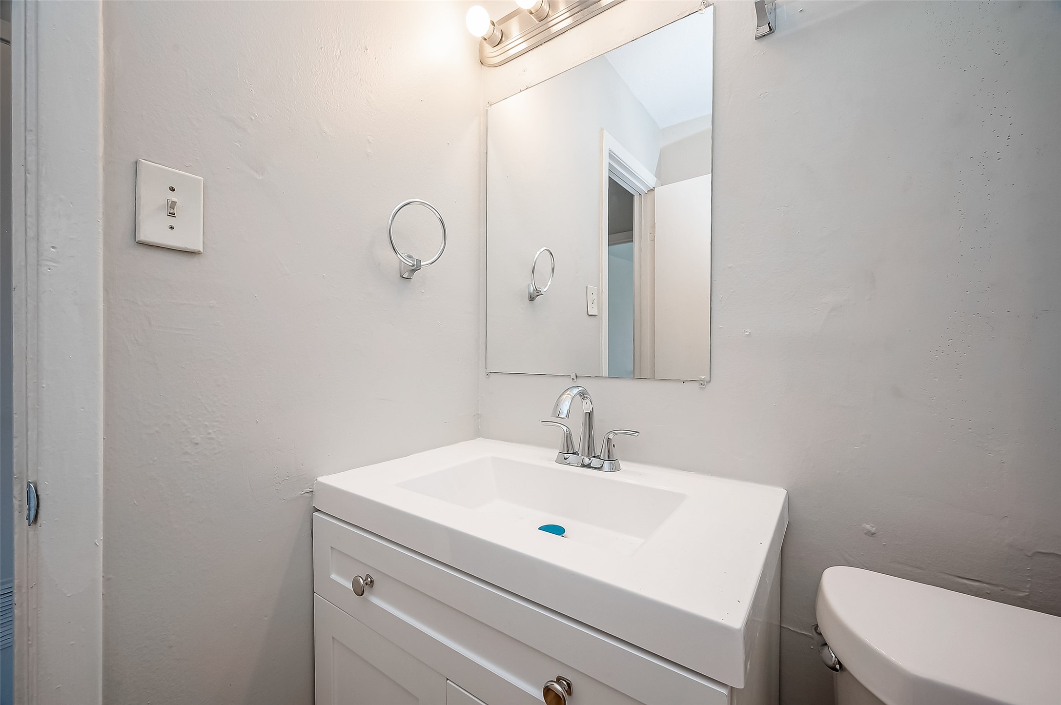 8814 Manus Street, Unit 5 Houston, TX 77093 - Photo 26 of 27 This bathroom features a modern white vanity with a sleek faucet and a large mirror, complemented by soft lighting and neutral walls for a clean, bright look.