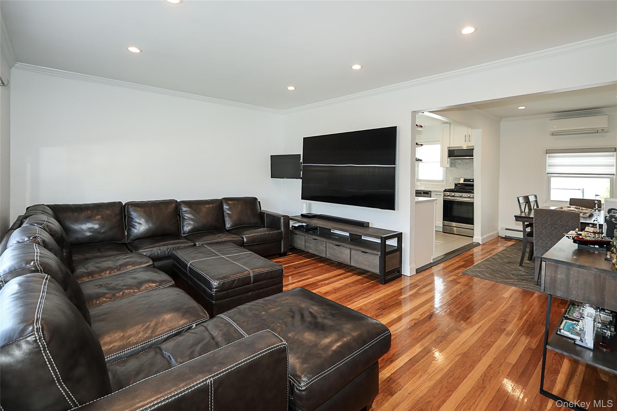 132 Bethel Road Albertson, NY 11507 - Photo 12 of 28 Living room with ornamental molding, light wood-style flooring, recessed lighting, a wall mounted AC, and baseboard heating