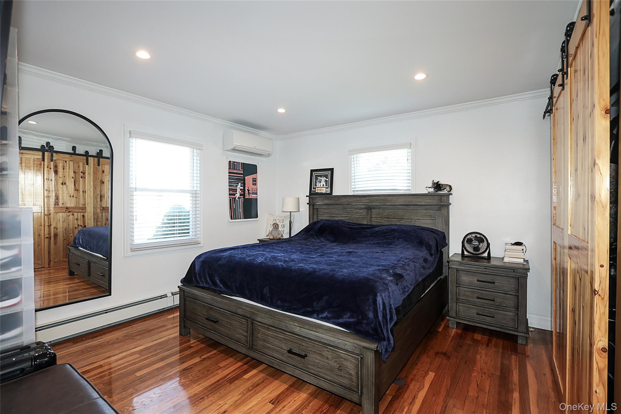 132 Bethel Road Albertson, NY 11507 - Photo 15 of 28 Bedroom with a barn door, crown molding, multiple windows, baseboard heating, and recessed lighting