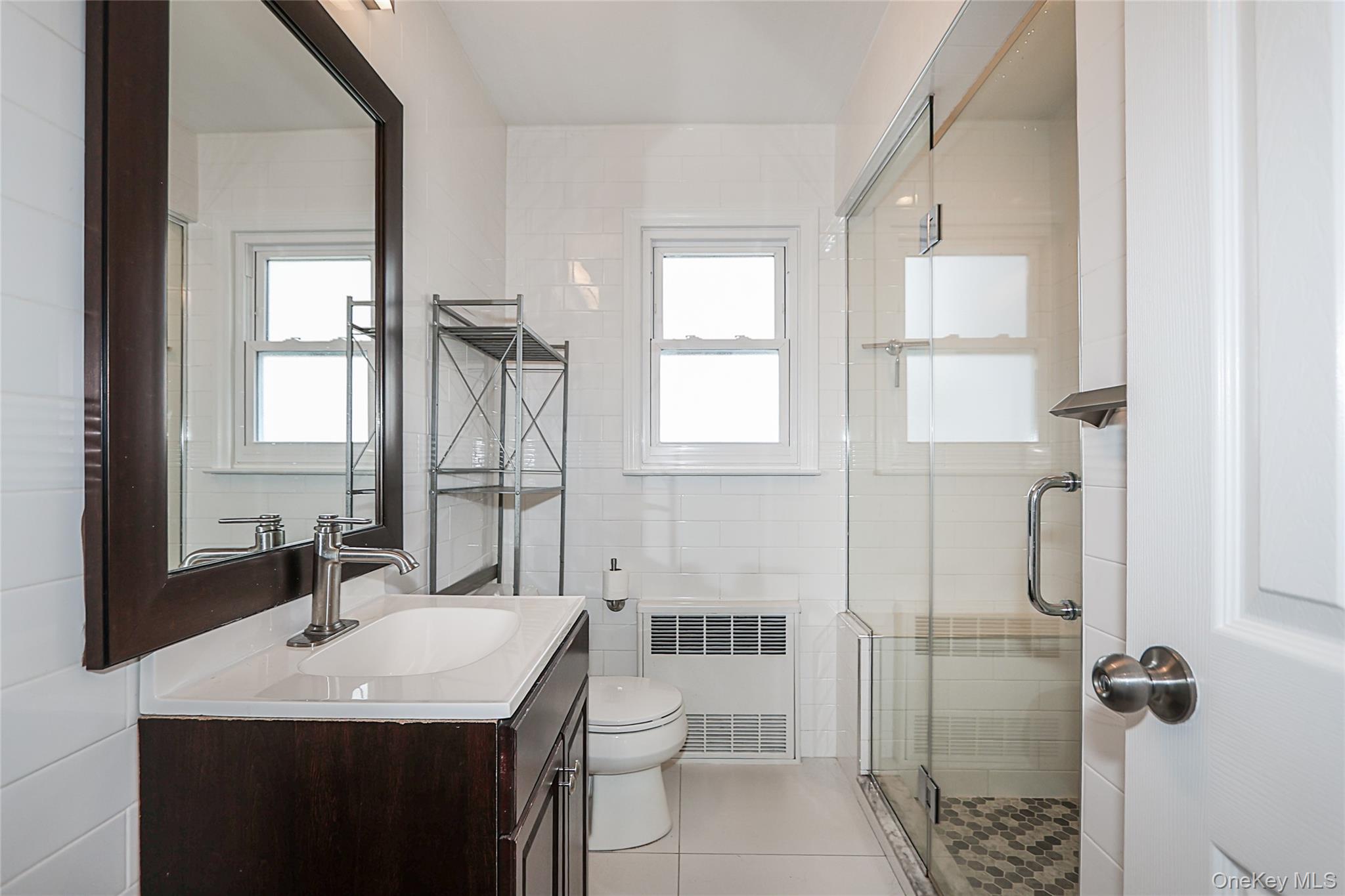 132 Bethel Road Albertson, NY 11507 - Photo 17 of 28 Full bath with vanity, radiator heating unit, a shower stall, tile walls, and light tile patterned flooring