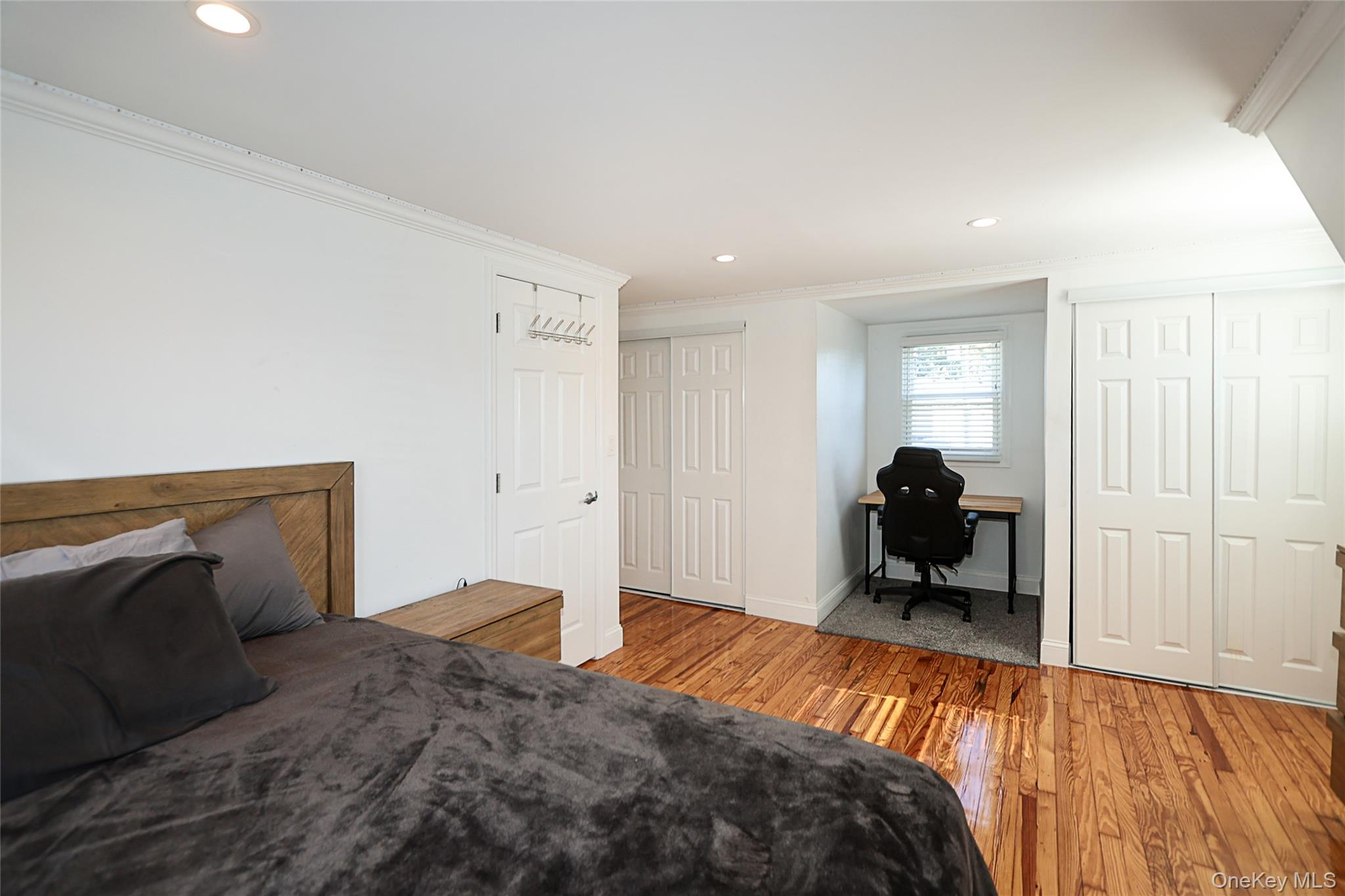 132 Bethel Road Albertson, NY 11507 - Photo 21 of 28 Bedroom with light wood-style flooring, crown molding, recessed lighting, an office area, and two closets