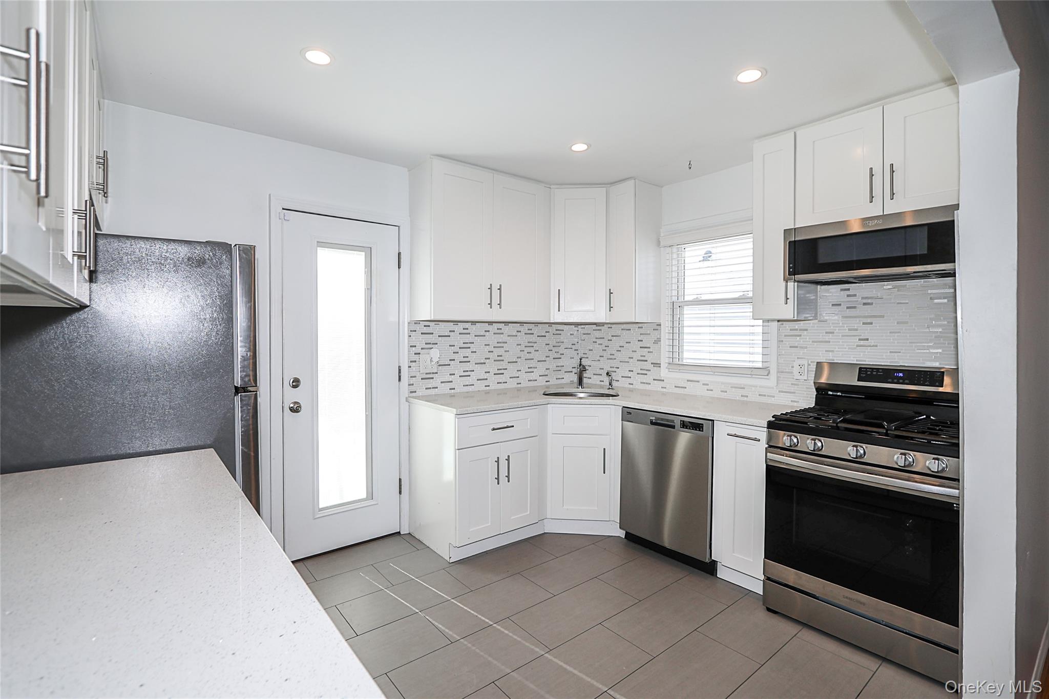 132 Bethel Road Albertson, NY 11507 - Photo 6 of 28 Kitchen featuring stainless steel appliances, backsplash, white cabinetry, light tile patterned floors, and recessed lighting