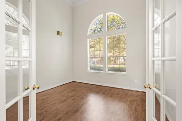 a view of an empty room with a window and wooden floor