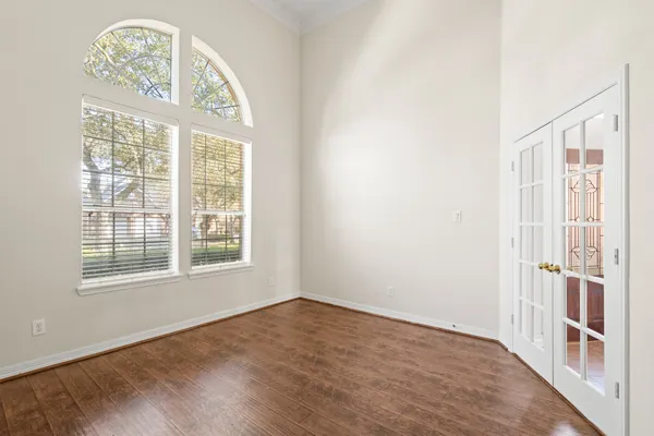 an empty room with wooden floor fan and windows