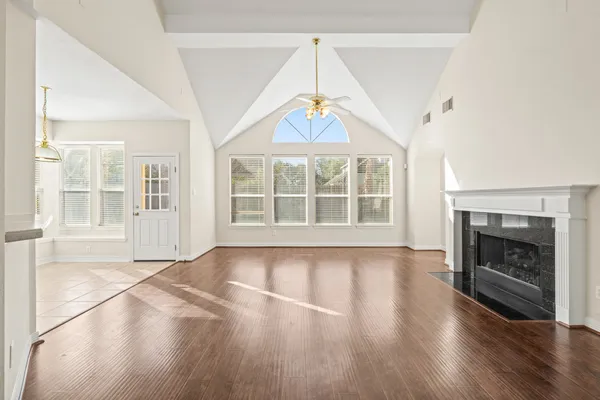an empty room with wooden floor fireplace and windows