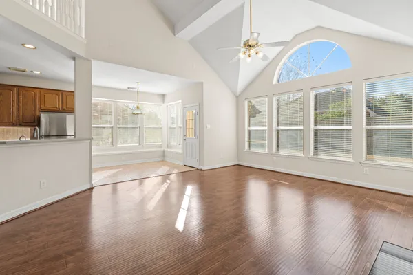 a view of an empty room with wooden floor and a window
