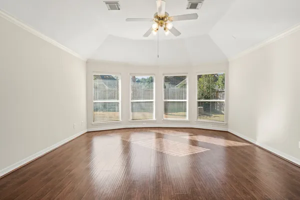 a view of an empty room with wooden floor and a window