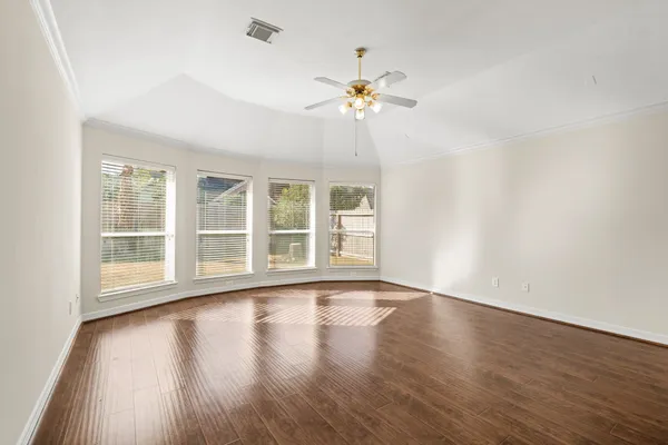 a view of an empty room with a window and wooden floor